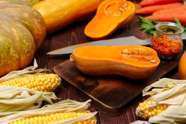 Küçük balkabağı, tahta kesme tahtasında bıçakla ikiye bölünmüş.