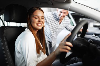 Genç ve çekici bir kadın galeride yeni bir araba arıyor.