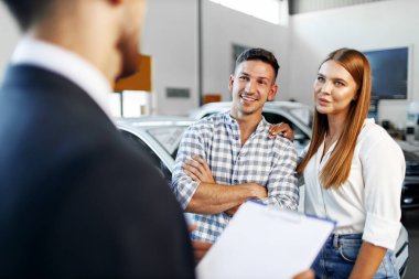 Erkek araba satıcısı yeni arabanın özelliklerini çifte anlatıyor.