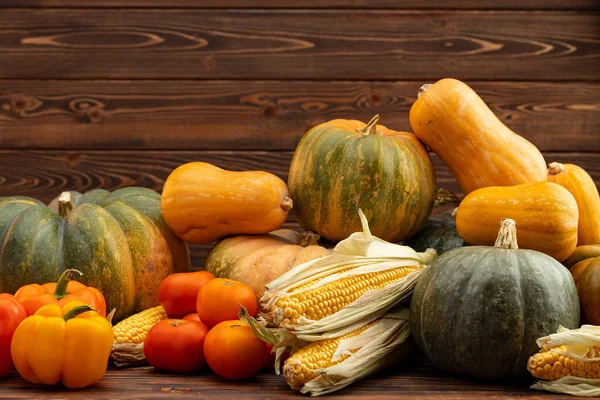 Dýně, kukuřice a rajčata na hnědém dřevěném pozadí — Stock fotografie