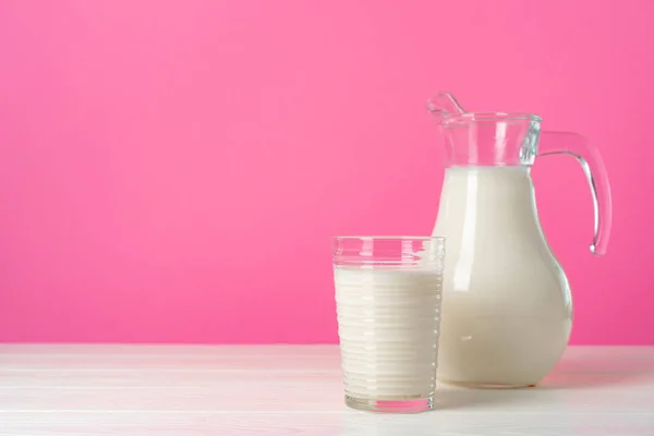 Artículos de vidrio con leche fresca sobre fondo pastel rosa — Foto de Stock