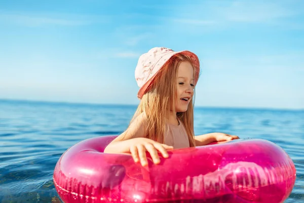 Jeune fille en panama rose nageant dans la mer avec cercle — Photo