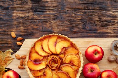 Elmalı turta ve tahta masada kırmızı elmalar.