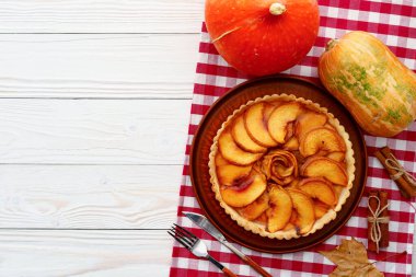 Elmalı tart masada, kabaklı ve kuru yapraklı.