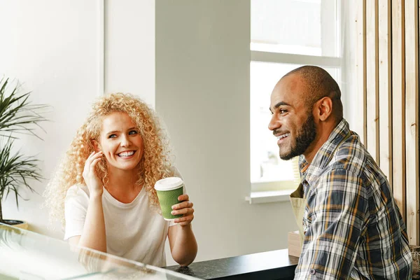 웃고 있는 금발 여자가 계산대에서 커피숍 웨이터와 이야기하고 있다 — 스톡 사진