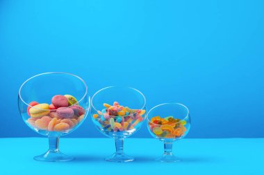 Mavi zemin üzerinde renkli şekerler bulunan cam kaplar