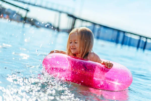 Petite fille avec cercle gonflable rose se baignant dans la mer — Photo