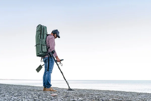 Человек с металлоискателем ищет потерянные сокровища на пляже — стоковое фото