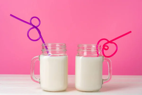 Скляні банки зі смаком молочних коктейлів на рожевому фоні — стокове фото