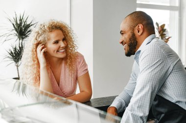 Gülümseyen sarışın kadın tezgahtaki garsonla konuşuyor.