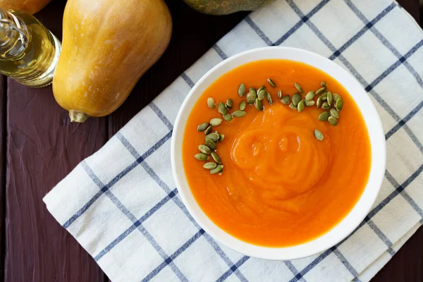 Top view of pureed pumpkin soup in a white bowl on dark table — Stock Photo, Image