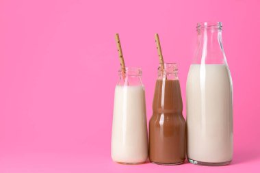Pembe arka planda aromalı milkshake dolu cam kavanozlar.