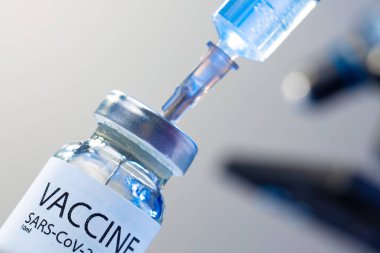 Covid-19 aşı şişesi. İçinde şırınga var. Aşıyı alıyor.