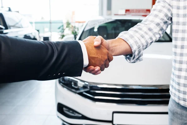 Müşteri otomobil galerisinde profesyonel araba satıcısıyla el sıkışıyor. — Stok fotoğraf