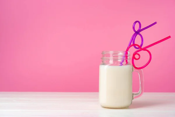 Artículos de vidrio con leche fresca sobre fondo pastel rosa — Foto de Stock