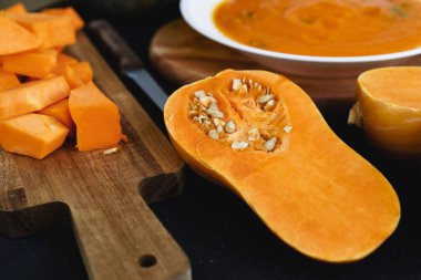 Masadaki tahta tahtada çiğ balkabağı parçaları kes.