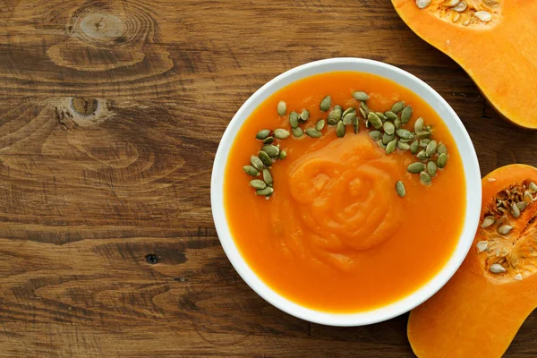 Top view of pureed pumpkin soup in a white bowl on dark table — Stock Photo, Image