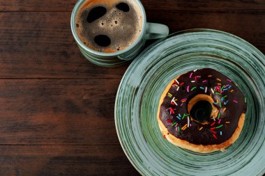 Yeşil tabakta jöleli çörek ve bir fincan kahve.