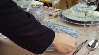 Masayı hazırlayan kadına yakın durun. Ev hanımı ya da garson elleri yemek masasına tabak koyuyor.