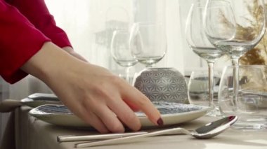 Masayı hazırlayan kadına yakın durun. Ev hanımı ya da garson elleri yemek masasına tabak koyuyor.
