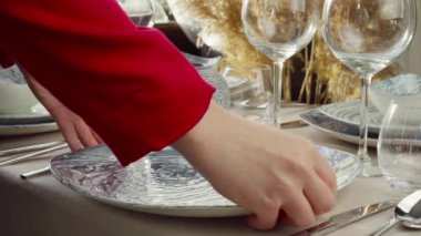 Masayı hazırlayan kadına yakın durun. Ev hanımı ya da garson elleri yemek masasına tabak koyuyor.