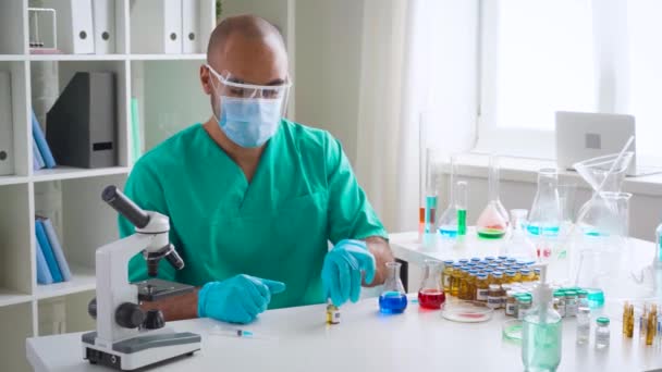 Virologiste scientifique se préparant à injecter le vaccin dans une seringue à partir d'un flacon assis à table en laboratoire — Video