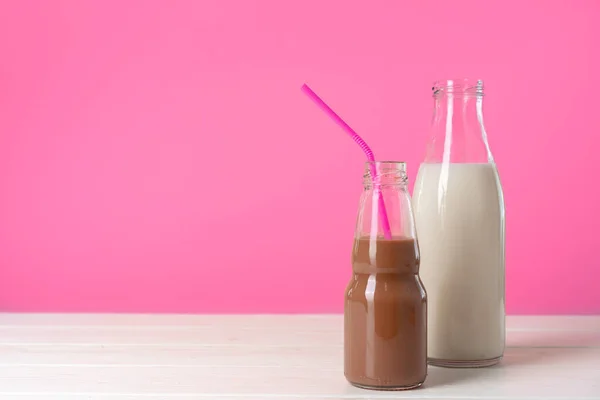 Due bottiglie di vetro di latte o frullato sullo sfondo rosa — Foto Stock