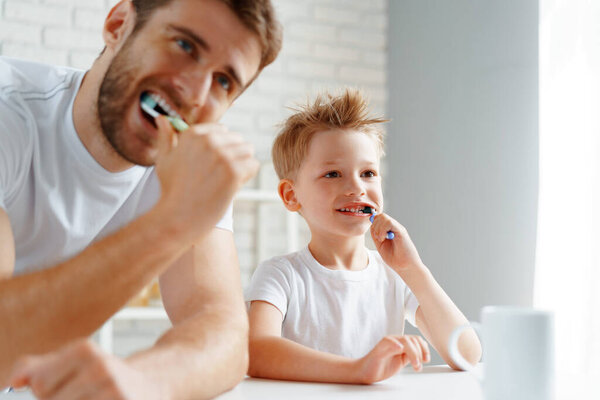 Папа и маленький сын чистят зубы вместе