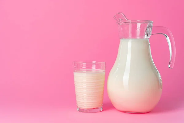 Artículos de vidrio con leche fresca sobre fondo pastel rosa — Foto de Stock