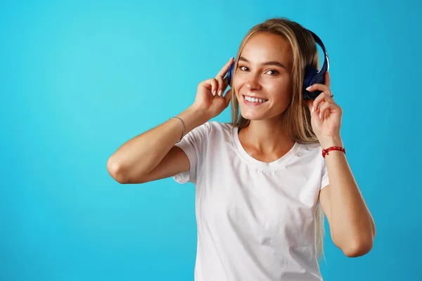 파란 헤드폰을 낀 음악을 듣고 있는 긍정적 인 젊은 여성 — 스톡 사진