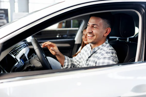 Joven cliente alegre compra un coche nuevo en un concesionario — Foto de Stock