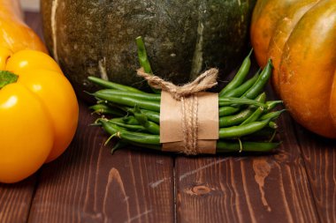 Balkabakları, dolma biber ve kahverengi ahşap masada bir demet yeşil fasulye.