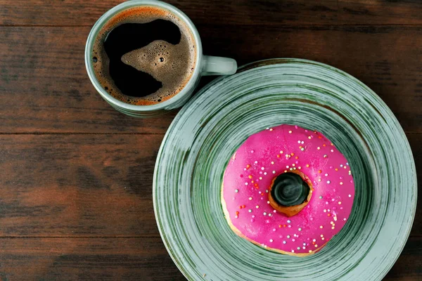 Glazed donut on green plate with cup of coffee — Stock Photo, Image