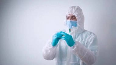 Koruyucu giysi ve maske giyen doktor ya da bilim adamı bir ampul aşı, koronavirüs konsepti taşıyor.