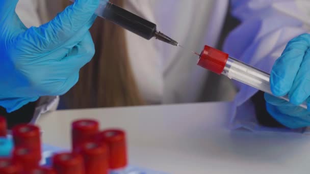 Doctor pours blood from a syringe to test tube close up — Stock Video