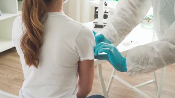 Doctor en traje ptotective hacer una inyección de vacuna a una paciente femenina en un hospital — Vídeos de Stock