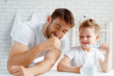 Baba ve küçük oğlu birlikte diş fırçalıyorlar.