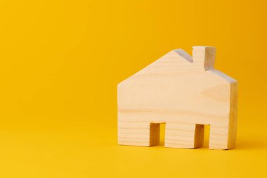 Sarı arka planda ahşap küçük ev modeli