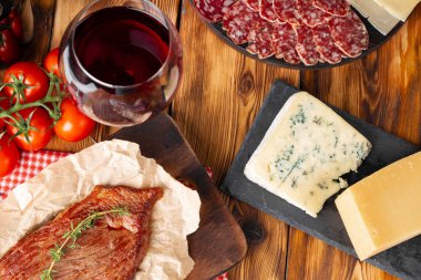 Ahşap masada kırmızı şarap bardağı ve peynir kalıpları