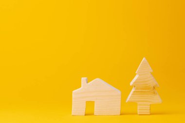 Sarı arka planda ahşap küçük ev modeli