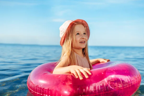 Jeune fille en panama rose nageant dans la mer avec cercle — Photo