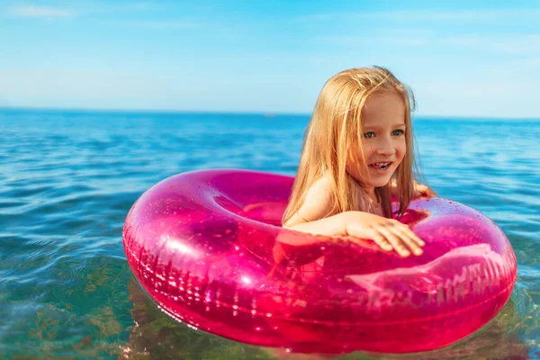 Petite fille avec cercle gonflable rose se baignant dans la mer — Photo