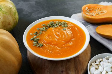 Siyah bir masada ev yapımı balkabağı çorbası.