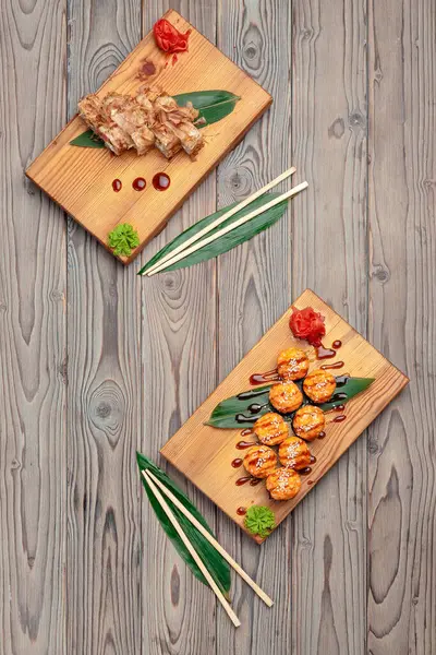 Rolos de sushi servidos em placas em fundo de madeira escura — Fotografia de Stock