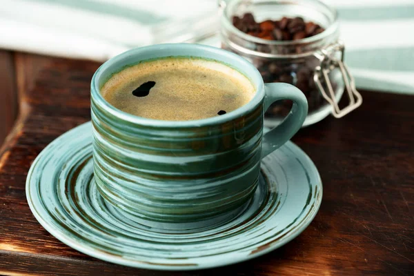 Green cup of coffee on saucer on wooden table — Stock Photo, Image