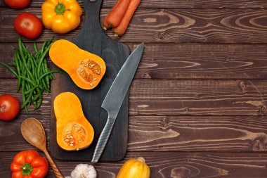 Küçük balkabağı, tahta kesme tahtasında bıçakla ikiye bölünmüş.