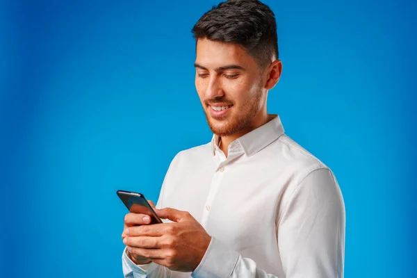 Beyaz gömlekli genç adam akıllı telefonunu kullanıyor. — Stok fotoğraf