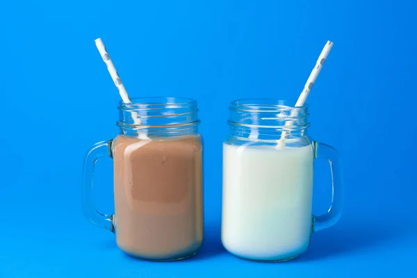 Słoik szklany ze świeżym mlekiem na niebieskim tle — Zdjęcie stockowe