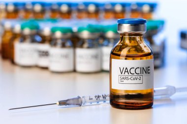 Laboratuar masasında şırınga olan Covid-19 aşı şişesi.