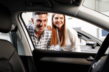 Young couple choosing their new car in a car shop clipart